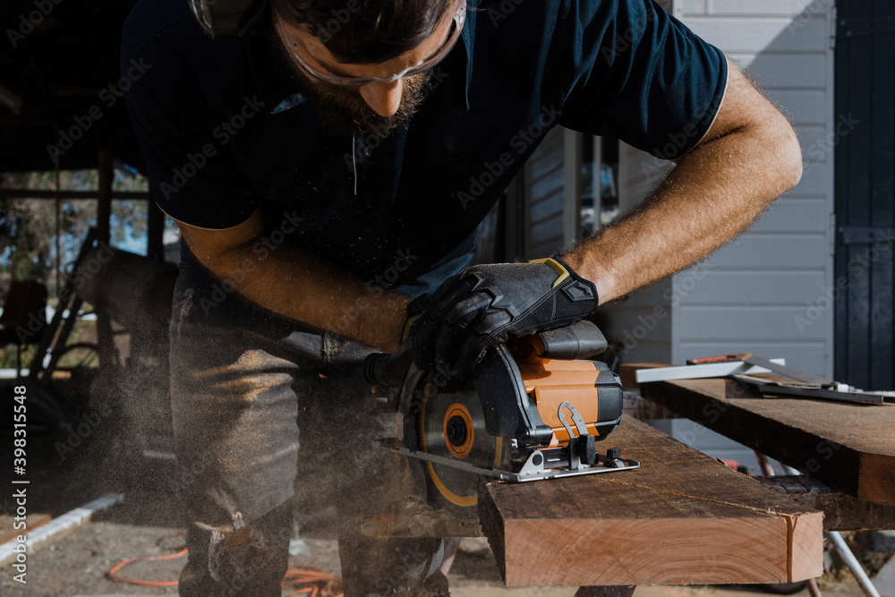 A man in safety apparel using a circular saw A man in safety apparel using a circular saw