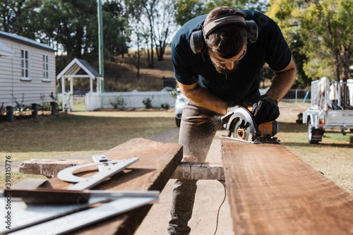 A man in safety apparel using a circular saw
