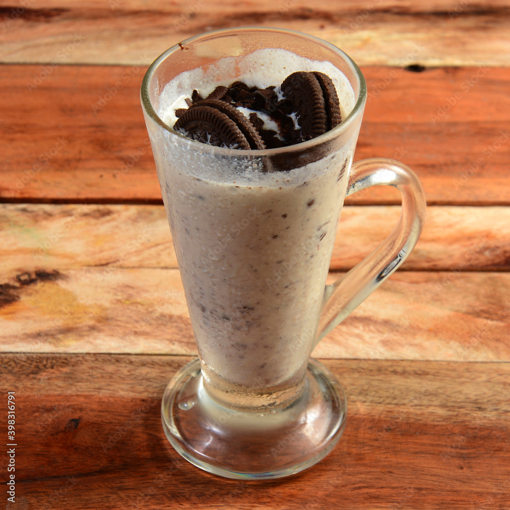 Oreo biscuit Milkshake, blended with oreo biscuits and icecream, served in a glass over a rustic wooden background, selective focus on top Oreo biscuit Milkshake, blended with oreo biscuits and icecream, served in a glass over a rustic wooden background, selective focus on top