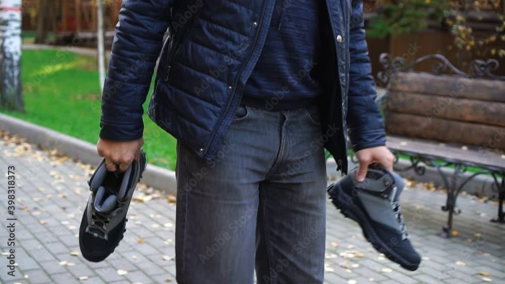 Unrecognizable man carries shoes in his hands Unrecognizable man carries shoes in his hands