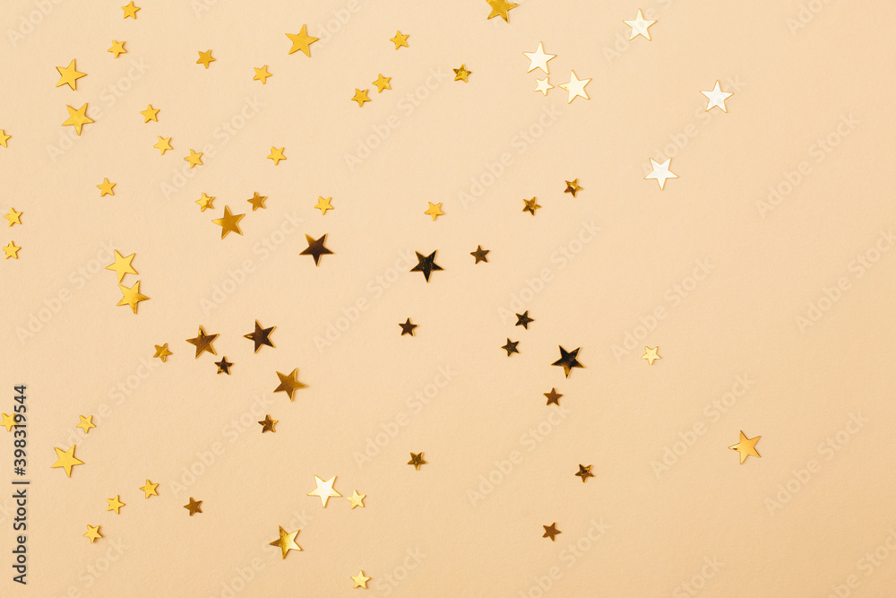 Gold confetti on beige paper background. Festive holiday backdrop. Birthday congratulations Christmas New Year. Flat lay, top view, copy space. Gold confetti on beige paper background. Festive holiday backdrop. Birthday congratulations Christmas New Year. Flat lay, top view, copy space.