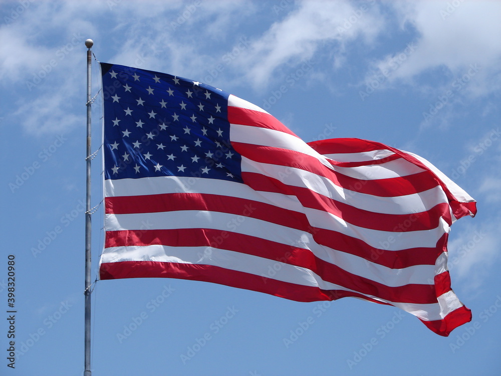 American Flag, stars and stripes, blowing in the wind with a blue sky behind