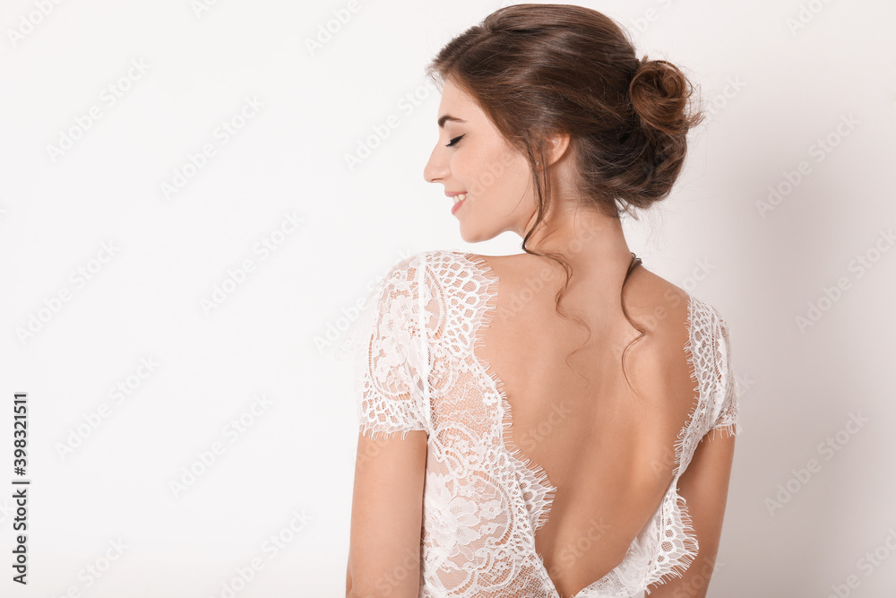 Young bride wearing beautiful wedding dress on light background Young bride wearing beautiful wedding dress on light background