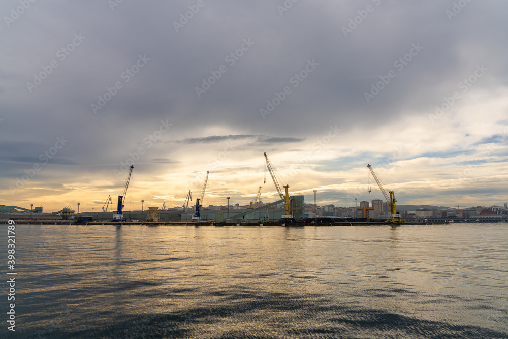 a view of the industrial port and harbor in La Coruna in golden morning light