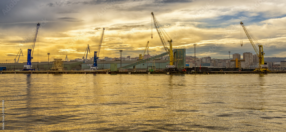a view of the industrial port and harbor in La Coruna in golden morning light