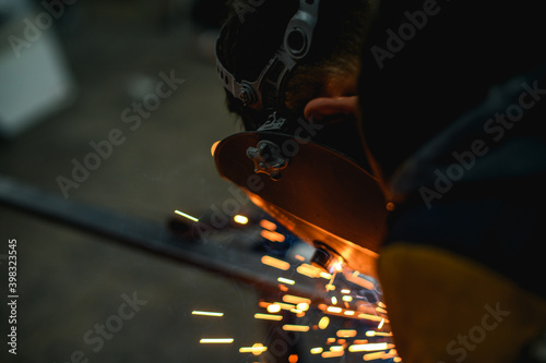 Selective focus of welder in protective mask working with welding in workshop 