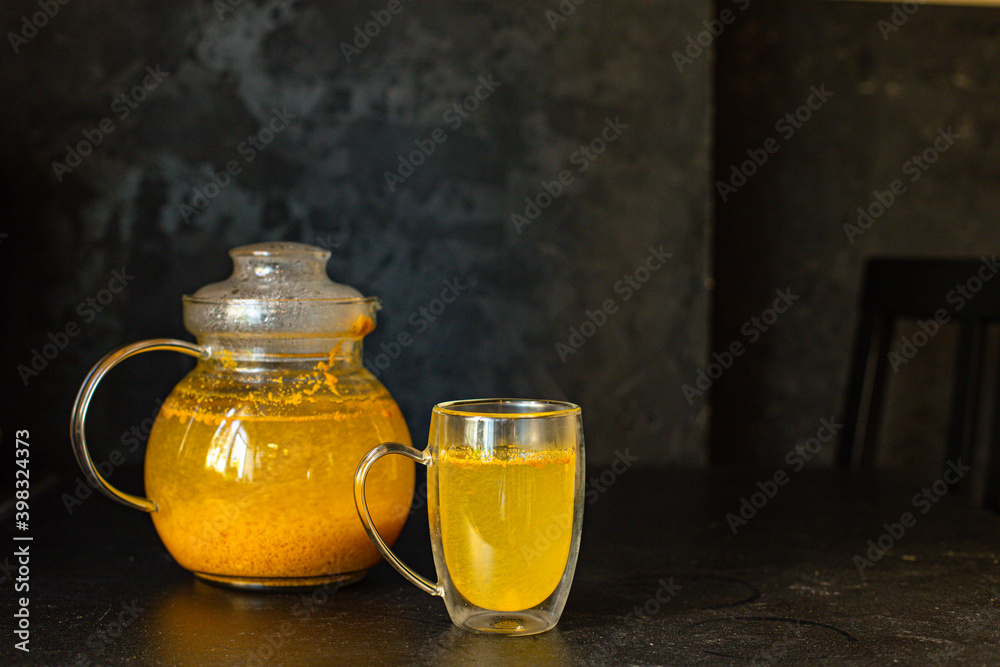 Obraz premium tea sea ​​buckthorn in a teapot and in a transparent cup on the table christmas new year hospitality drink healthy meal snack ingredient top view copy space for tex