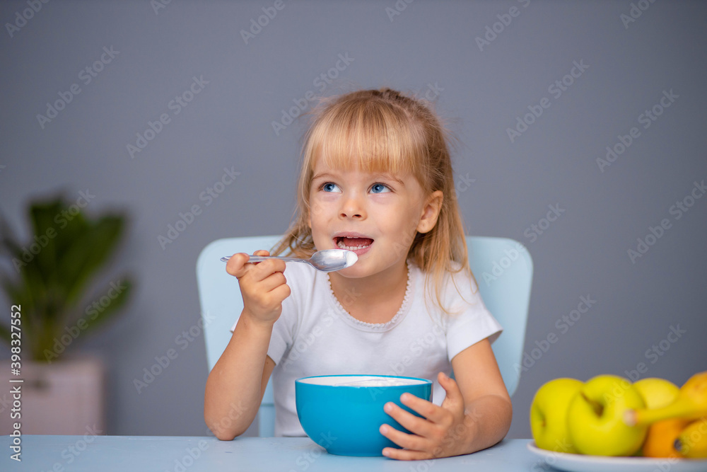 Cute little child girl eating yogurt indoors Cute little child girl eating yogurt indoors