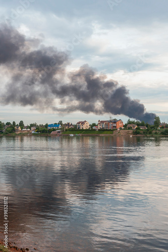 view of the Neva River with a cargo ship at the pier and a dangerous cloud of black smoke from a burning building. Fire and disaster concept