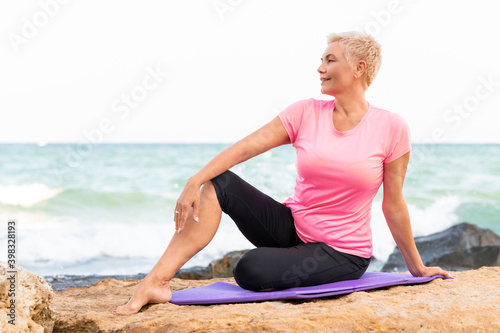 A senior woman sitting at a beach before yoga exercise