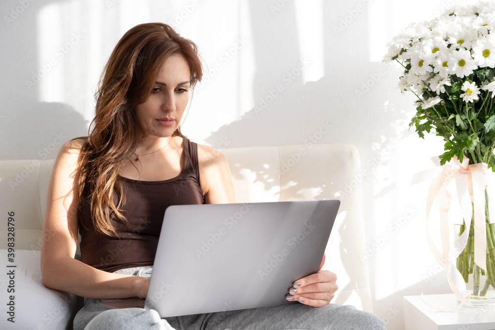 Casual woman using laptop in white bedroom. shadow in room. Casual woman using laptop in white bedroom. shadow in room.