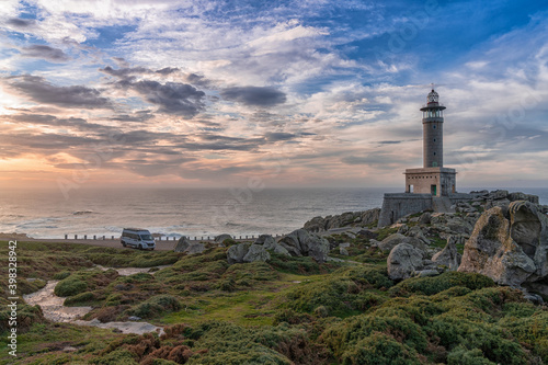 sunset at the Punta Nariga lighthouse in Galicia with a gray camper van parked there