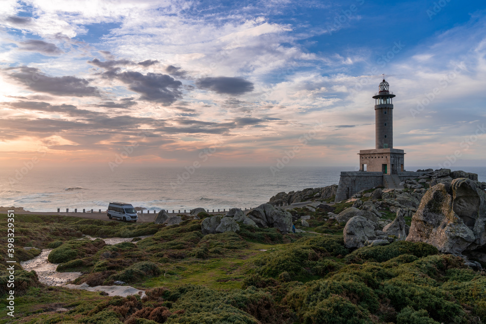 sunset at the Punta Nariga lighthouse in Galicia with a gray camper van parked there