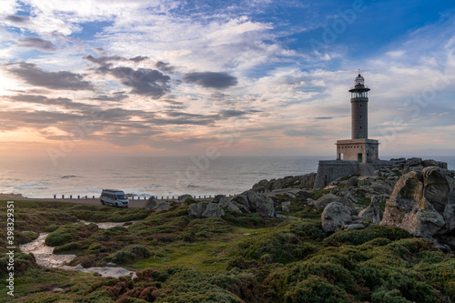 sunset at the Punta Nariga lighthouse in Galicia with a gray camper van parked there