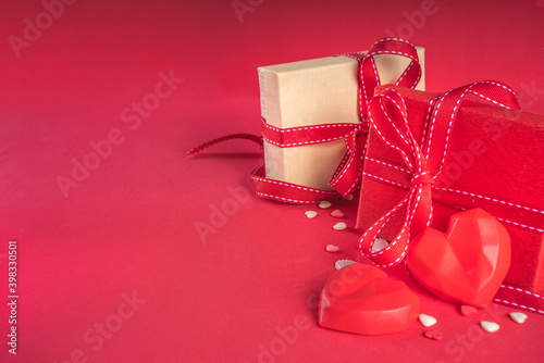 Valentine greeting card background, with gift box festive ribbons, assorted hearts on red table backdrop top view copy space for text. Valentine's day concept.