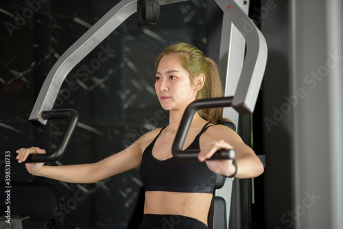 Beautiful Asian fitness woman is training with sport equipment in fitness gym. Fitness and health concept .