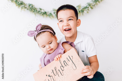 the cheerful boy laughs and hugs his younger sister