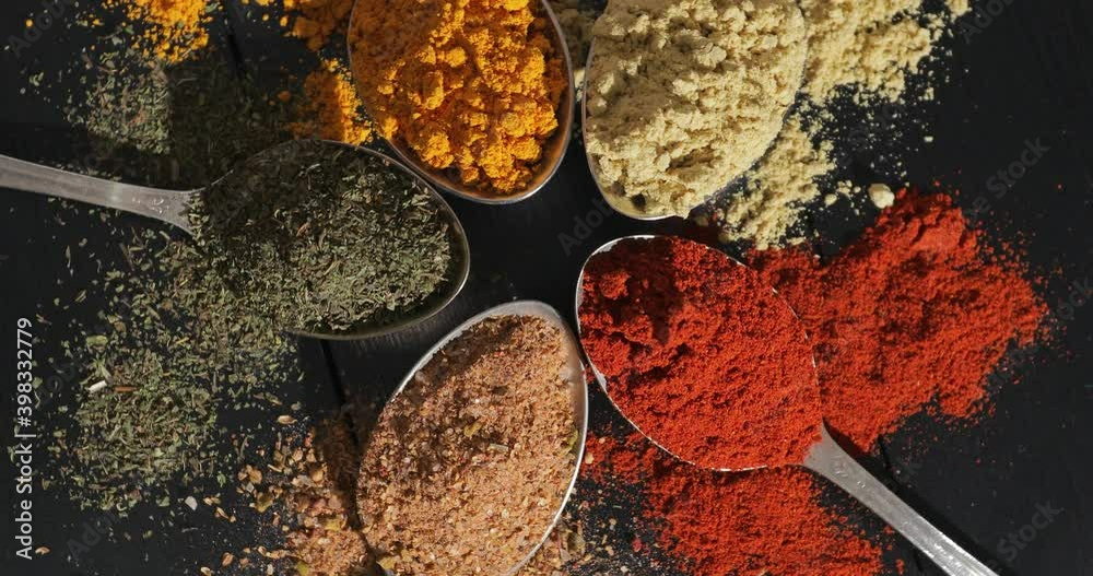 Spoons with different spices on rotating board