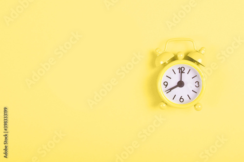 Analogue illuminating alarm clock showing eight in the morning on living yellow background. Flat lay with copy space. Color of 2020.