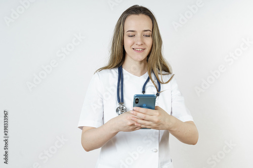 Medicine and health concept. Young woman doctor message in mobile phone.