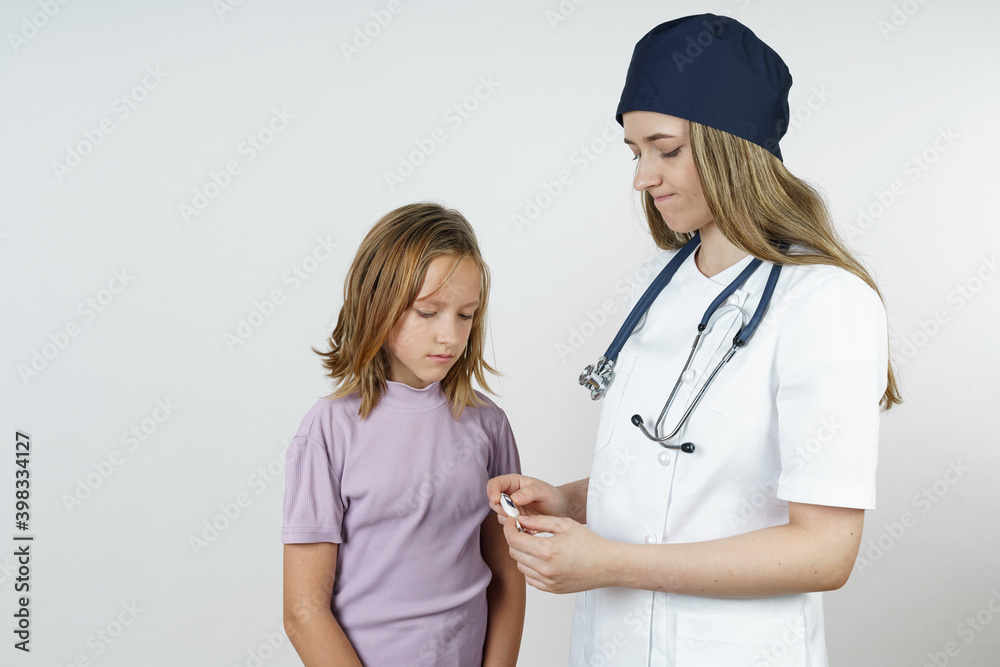 Medicine and health concept. A young female doctor looks at the temperature measurement of a teenage girl. Medicine and health concept. A young female doctor looks at the temperature measurement of a teenage girl.
