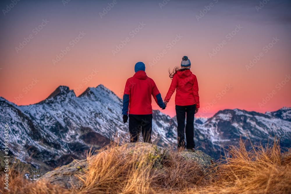 couple of people watch the sunset from a mountain