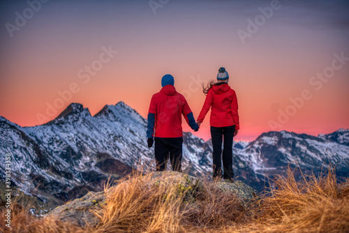 couple of people watch the sunset from a mountain