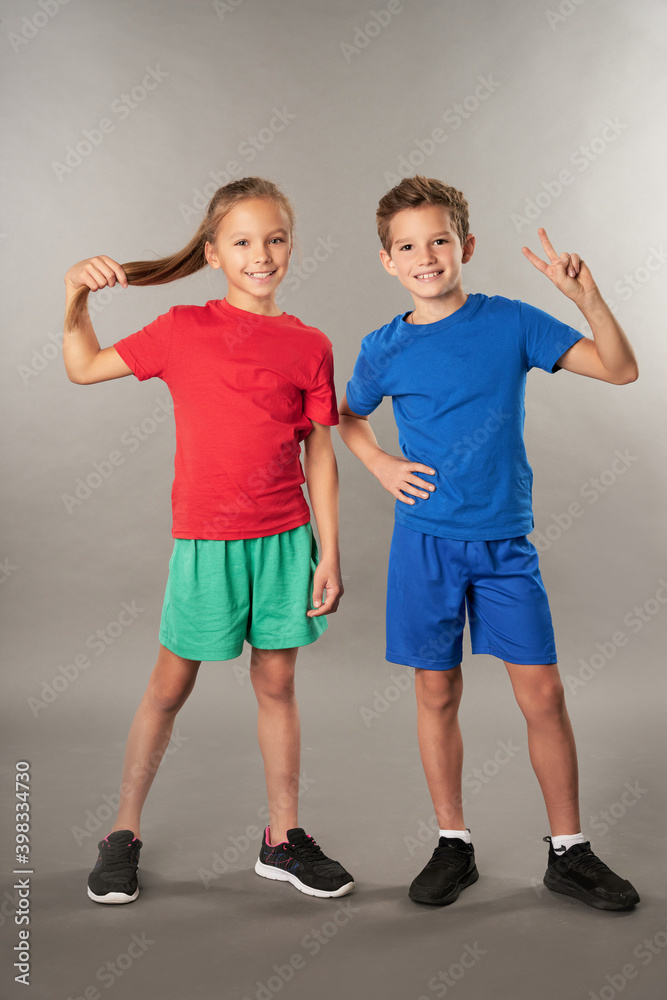 Joyful boy and girl standing against gray background Joyful boy and girl standing against gray background