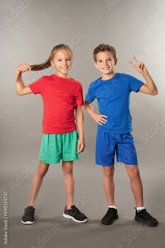 Joyful boy and girl standing against gray background