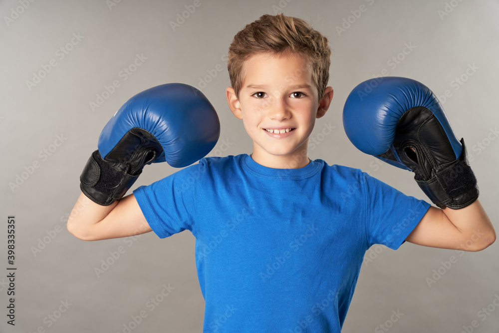 Cute boy in boxing gloves standing against gray background Cute boy in boxing gloves standing against gray background