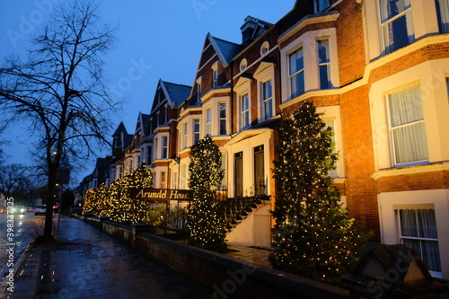 Multiple festive decorated houses in Cambridge city, people putting christmas trees in front of their houses as the holidays approach in december