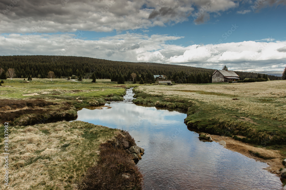 Fall spring view of mountain landscape, fresh cold stream and large meadow at Jizerka settlement,Czech republic. Autumn nature in cloudy day.Peat bogs of Jizerka.Clear tranquil water.