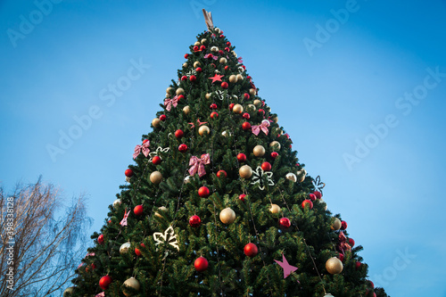 Large Christmas tree with toys on a blue sky background.
