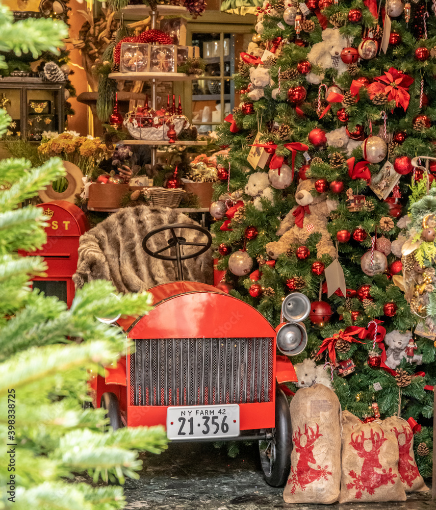 Petite voiture rouge dans un magasin avec des décorations de noël et des  branches de sapin Photos