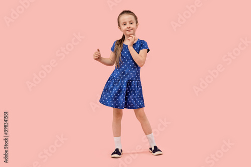 Beautiful baby girl dancing on pink isolated background. Beautiful blue polka dot dress. © Evgenia