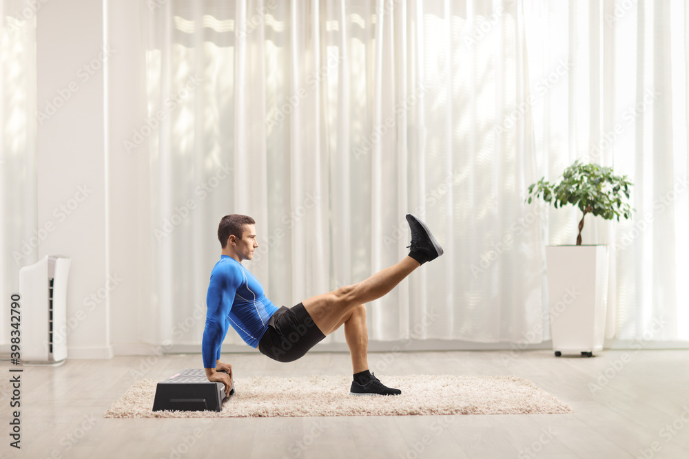 Fit strong man exercising on a step aerobic platform with his leg up Fit strong man exercising on a step aerobic platform with his leg up