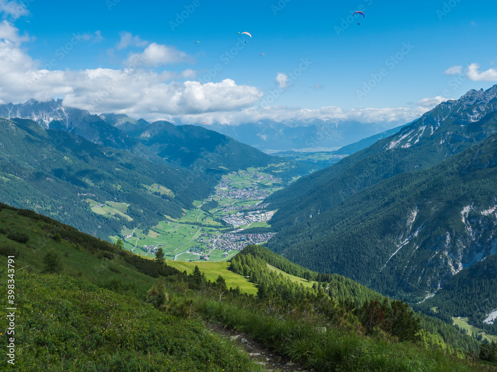 View over green Stubai valley and Neustift im Stubaital village from Elferhutte with moutain peaks and kites. Tirol Alps, Austria, Summer blue sky, white clouds View over green Stubai valley and Neustift im Stubaital village from Elferhutte with moutain peaks and kites. Tirol Alps, Austria, Summer blue sky, white clouds