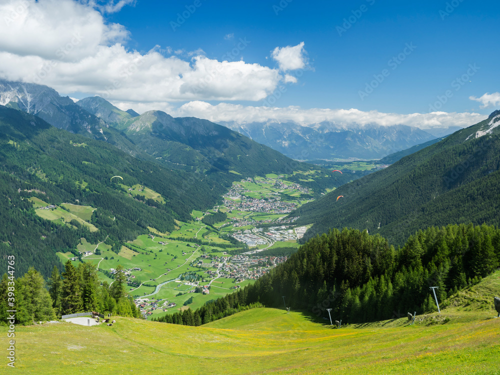 View over green Stubai valley and Neustift im Stubaital village from Elferhutte with moutain peaks and kites. Tirol Alps, Austria, Summer blue sky, white clouds View over green Stubai valley and Neustift im Stubaital village from Elferhutte with moutain peaks and kites. Tirol Alps, Austria, Summer blue sky, white clouds