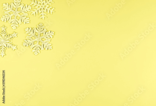 Illuminating and bright yellow holiday Christmas background with shiny glitter snowflakes with copy space for text. Color trend of the year 2021.