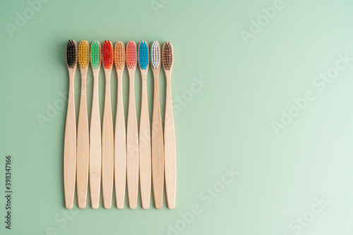 A set of Eco-friendly antibacterial toothbrushes made of bamboo wood on a light green background. Environmental care trends © Kate