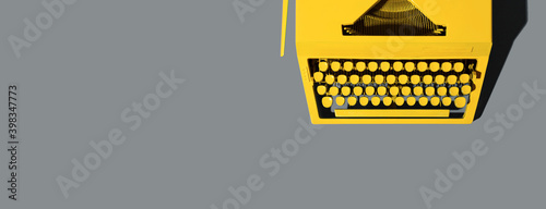 Yellow bright typewriter on gray. The color of the year 2021 is illuminating yellow and the ultimate gray. Copy space banner