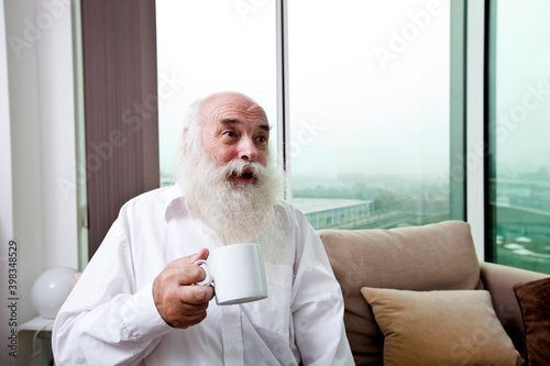 Happy senior man holding coffee cup at home