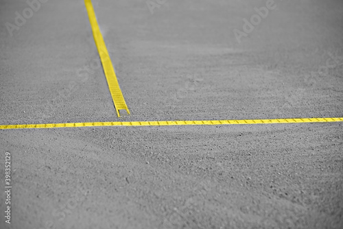 Gray sand and gravel base of the tennis court with yellow lines. Blurred background. Colors of the year 2021.
