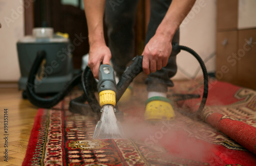 The process of cleaning carpets with a steam vacuum cleaner. An employee of a cleaning company cleans the carpet using steam.