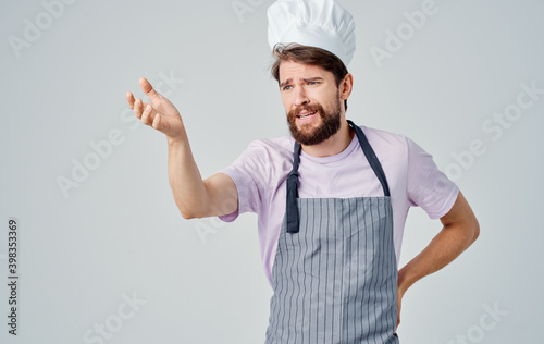 A man in a gray aprons and a headdress is gesturing with his hands as a professional cook
