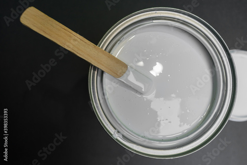 can of white paint, stirring with palette, top view black background.