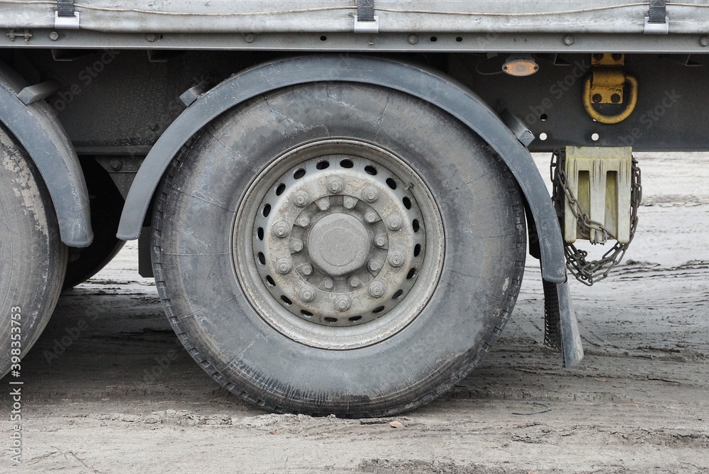 one large dirty wheel on a truck stands on gray asphalt