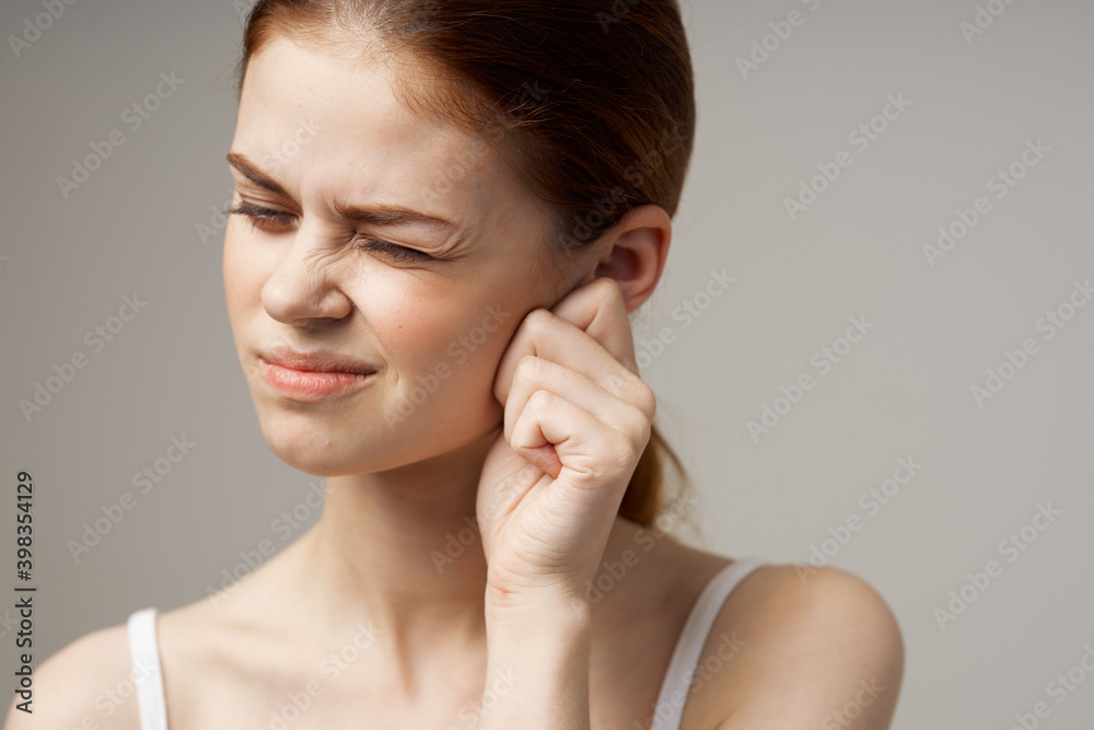 woman in white t-shirt holding ears discontent migraine health problems woman in white t-shirt holding ears discontent migraine health problems