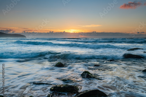 Sunrise seascape with light cloud, waves and rocks