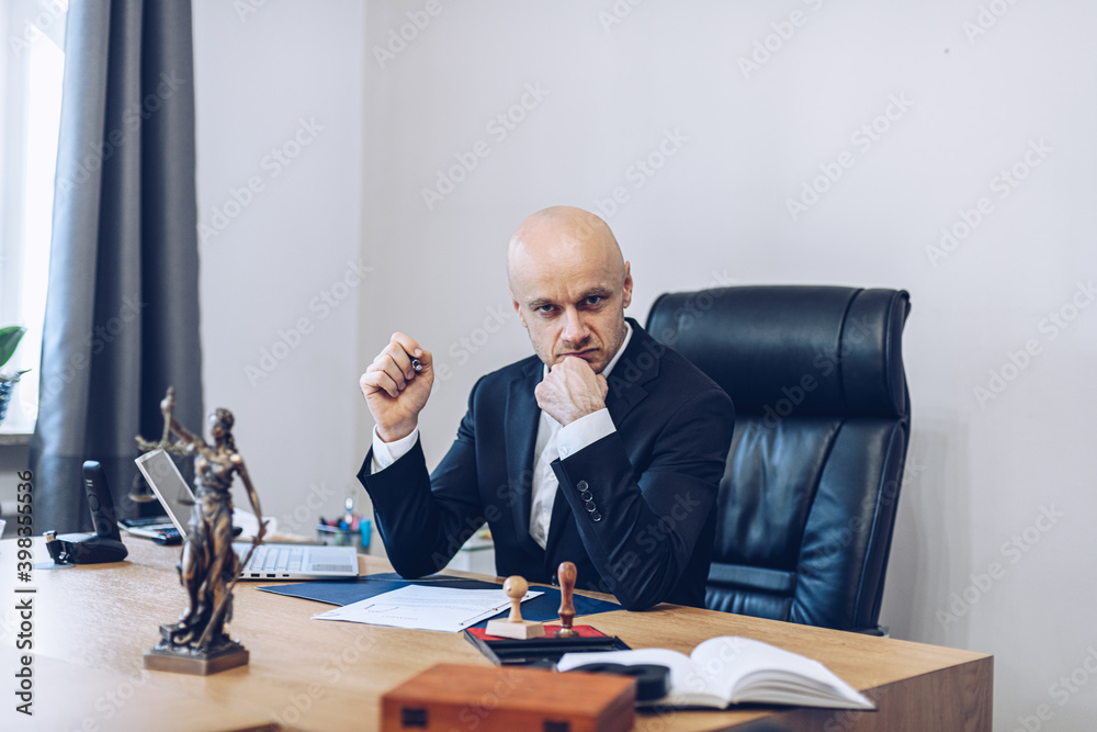 A handsome lawyer is sitting at a wooden table waiting for a contract to be signed by the customer. A handsome lawyer is sitting at a wooden table waiting for a contract to be signed by the customer.
